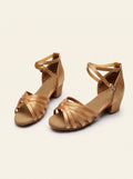Chaussures de danse latine fille à brides croisées, satin caramel, talon 3,5 cm, sur fond crème