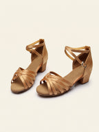 Chaussures de danse latine fille à brides croisées, satin caramel, talon 3,5 cm, sur fond crème